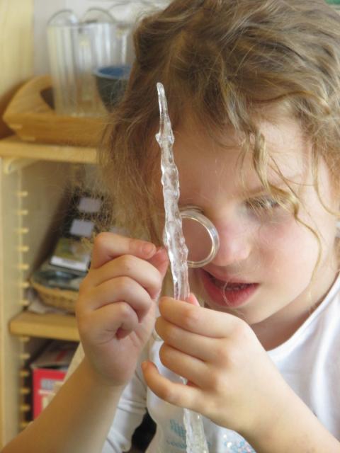 Girl looking at ice with a magnifying glass