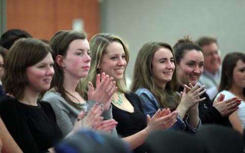 A group of young women clap in the audience at an Age of Champions event