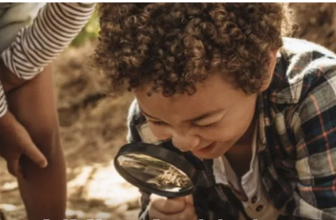 Child looking through magnifying glass