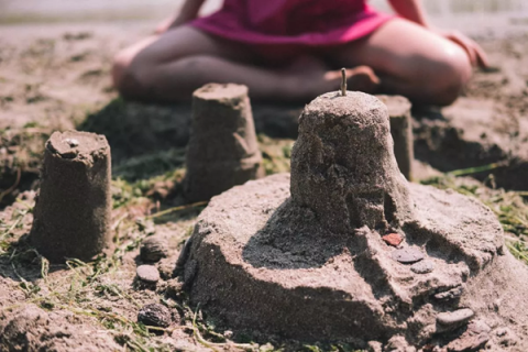Child sitting in sand building sandcastles