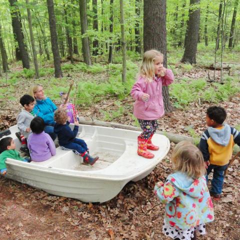 group of children playing in boat in the woods